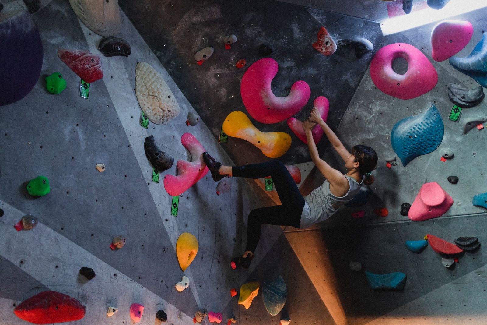 Boulderaar op een kleurrijke boulderwand in een Nederlandse boulderhal